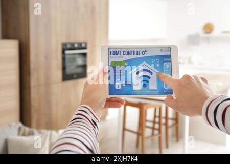 Young man with smart home security system control panel in kitchen, closeup Stock Photo