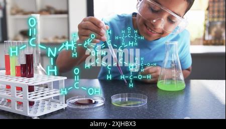 Conducting science experiment, child with safety goggles using pipette over chemical formulas image Stock Photo