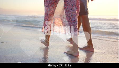 Image of hearts moving over diverse couple in love on beach in summer Stock Photo