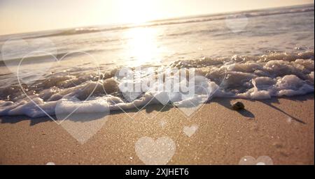 Image of hearts moving over beach in summer. Love, romance, valentine's day and vacation concept digitally generated image. Stock Photo