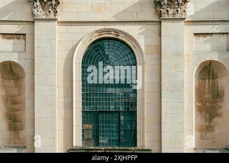 A large arched window with a grid of panes, framed by an ornate stone structure in Cambridge, UK. Stock Photo