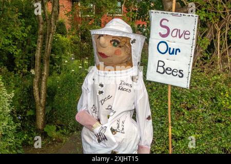 'Save our bees'   Create a honey bee haven, grow bee-friendlu plants. Wildlife plea sign on Dummy in beekeeper suit  Penwortham, Preston, UK Stock Photo