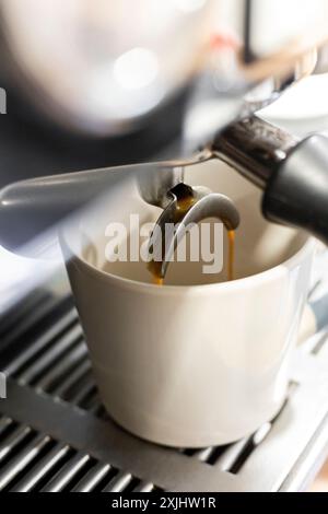 Coffee pouring into a coffee cup in a restaurant coffee machine. Stock Photo