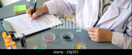 Unrecognizable female scientist examining glitter samples in petri dishes on laboratory Stock Photo