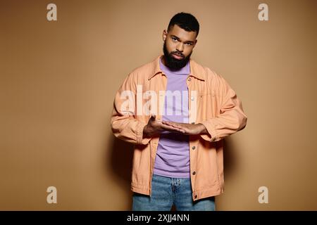 Handsome man standing with hands in pockets against vibrant backdrop. Stock Photo