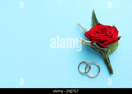 Small stylish boutonniere and rings on light blue background, top view. Space for text Stock Photo