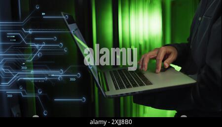 Image of motherboard over midsect5ion of biracial male it tech using laptop in server room Stock Photo