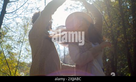 Happy multiethnic couple carefree Hispanic woman female Arabic Indian male boyfriend dancing together in park man spinning girlfriend moving rhythm Stock Photo