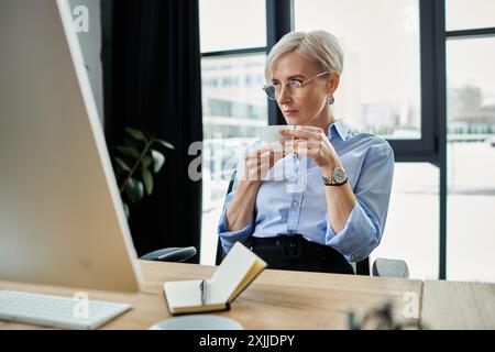 Middle-aged woman with short hair focused on her computer while working in her office Stock Photo