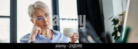 A middle aged businesswoman with short hair in a blue shirt peacefully holding a cup. Stock Photo