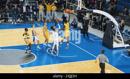 Basketball Championship Action on Live TV Channel: Yellow Team Defense Player Steals the Ball From Opponent, Passes the Ball Through Defence. Black Basketballer Scores a Successful Dunk with One Hand Stock Photo