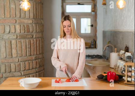 Young attractive blonde woman preparing healthy meal in her kitchen Stock Photo