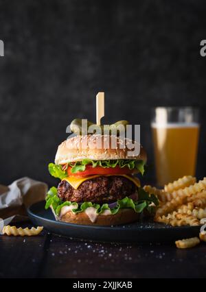 Close up of hamburger, french fries and beer on wood table. Stock Photo