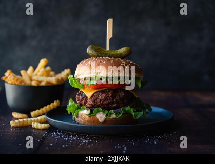 Hamburger and french fries on wood table with dark background. Stock Photo