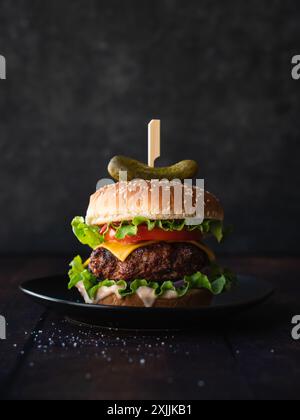 Close up of gourmet hamburger on wood table with dark background. Stock Photo