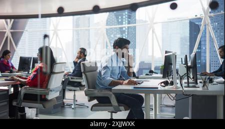 Group of Multicultural South Asian Men and Women Working in a Research Center, Collaborating on a Corporate Project. Indian Man Focused on a Task is Using Computer to Analyze Business Opportunities Stock Photo