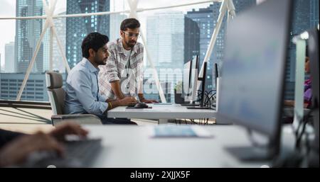 Two Indian Colleagues Having a Conversation While Busy Working on a Business Project. Software Engineer Talking with Project Manager During a Meeting. Teamwork in a Modern Corporate Office Stock Photo