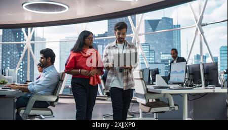 Young Team of South Asian Specialists Working on Desktop Computers at a Modern Workplace. Indian Software Developer Discussing a Financial Software Project with a Female Team Leader Stock Photo