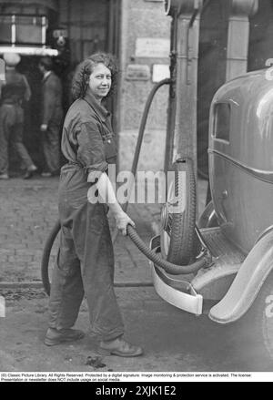 Petrol station in the 1930s. A female attendant is seen filling a car with petrol. Stock Photo