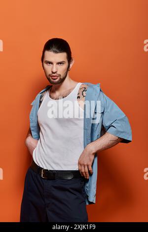 A stylish Caucasian man standing confidently in front of a bright orange wall. Stock Photo