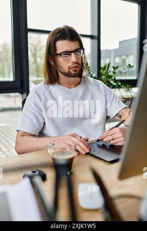 A focused man sits at a desk, utilizing a laptop for work. Stock Photo