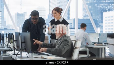 Diverse Colleagues Talking In Front Of Desktop Computer In Corporate Office With Megapolis Window View. Caucasian Male Developer Showing New Code To African CEO And His Female Assistant With Tablet. Stock Photo