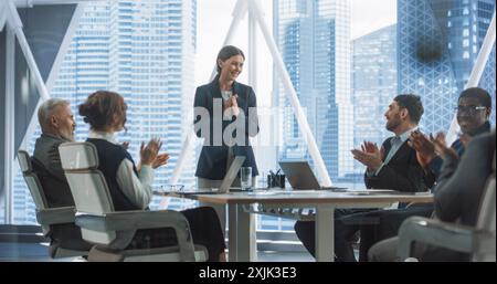 Caucasian Female Entrepreneur Talks With Senior Managers On Corporate Meeting In Modern Office. Diverse Employees Applauding After Businesswoman Reported Growth And Profit Of Tech Startup Company. Stock Photo