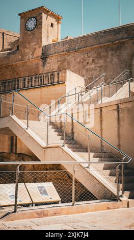 View of a historic stone fortress featuring a staircase leading up to the entrance under a clear blue sky. Stock Photo