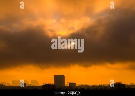 Morning over the city. Heavy clouds cover the sun in the dawn sky. Silhouettes of buildings in backlight Stock Photo