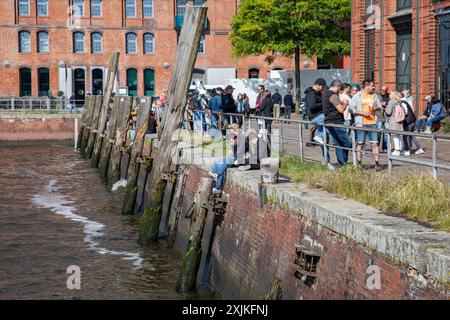 People relaxing and enjoying beverages on the bank of Elbe river outside Fischauktionshalle on Sunday morning in Hamburg, Germany Stock Photo