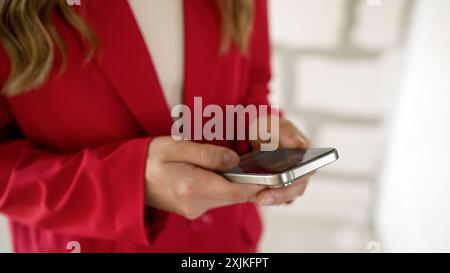 A girl writes SMS on a smartphone indoors. Girl holding a phone, close-up, searching on the phone. An unrecognizable girl holds the phone with both Stock Photo