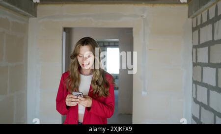 A girl writes SMS on a smartphone indoors. Girl holding a phone, close-up, searching on the phone. An unrecognizable girl holds the phone with both Stock Photo