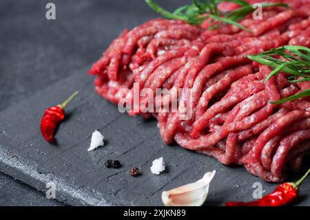 Raw minced meat on stone board with thyme, black peppers and garlic, butcher concept Stock Photo