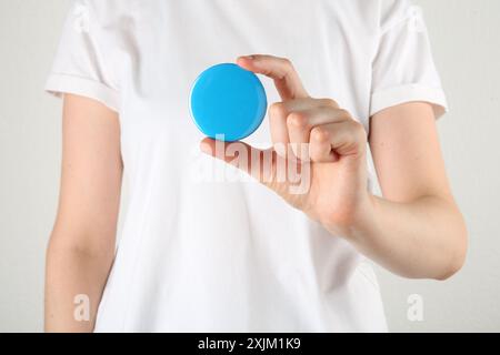 Woman with blank blue button badge on light background, closeup Stock Photo