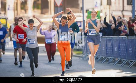 Women Supporting Women: Portrait of Happy Female Runners Participating in a Marathon. Group of Friends Celebrating Together and Congratulating Each Other on Crossing the Finish Line Stock Photo