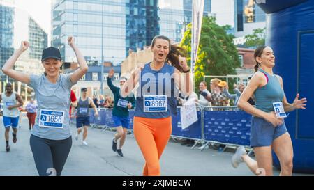 Women Supporting Women: Portrait of Happy Female Runners Participating in a Marathon. Group of Friends Celebrating Together and Congratulating Each Other on Crossing the Finish Line Stock Photo