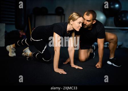Young sportswoman doing push-ups during exercise class with a coach in health club. Stock Photo
