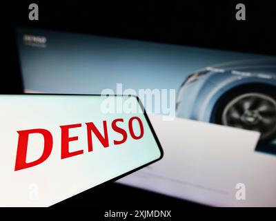 Stuttgart, Germany, 06-04-2022: Smartphone with logo of Japanese automotive company DENSO Corporation on screen in front of business website. Focus Stock Photo