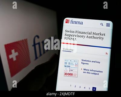 Stuttgart, Germany, 06-04-2022: Person holding cellphone with webpage of Eidgenoessische Finanzmarktaufsicht (FINMA) on screen in front of logo. Stock Photo