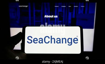 Stuttgart, Germany, 06-18-2022: Person holding smartphone with logo of US company SeaChange International Inc. on screen in front of website. Focus Stock Photo