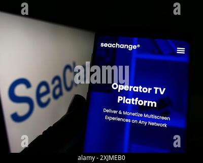 Stuttgart, Germany, 06-18-2022: Person holding smartphone with website of US company SeaChange International Inc. on screen in front of logo. Focus Stock Photo