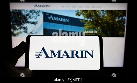 Stuttgart, Germany, 06-11-2022: Person holding smartphone with logo of biopharmaceutical company Amarin Corporation plc on screen in front of Stock Photo