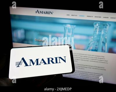 Stuttgart, Germany, 06-11-2022: Person holding cellphone with logo of biopharmaceutical company Amarin Corporation plc on screen in front of webpage. Stock Photo