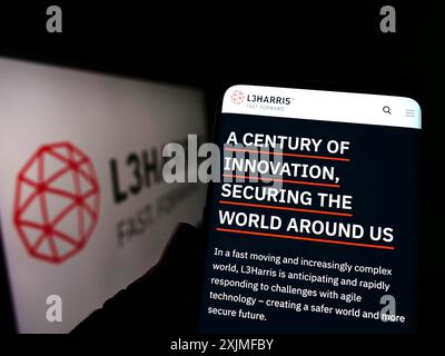 Stuttgart, Germany, 06-18-2022: Person holding cellphone with webpage of US aerospace company L3Harris Technologies Inc. on screen with logo. Focus Stock Photo