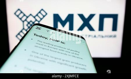 Stuttgart, Germany, 06-18-2022: Smartphone with webpage of Ukrainian company Myronivsky Hliboproduct (MHP) on screen in front of logo. Focus on Stock Photo