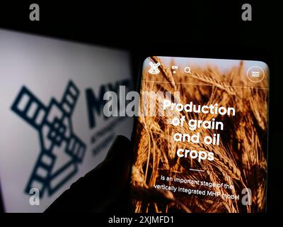 Stuttgart, Germany, 06-18-2022: Person holding cellphone with website of Ukrainian company Myronivsky Hliboproduct (MHP) on screen with logo. Focus Stock Photo