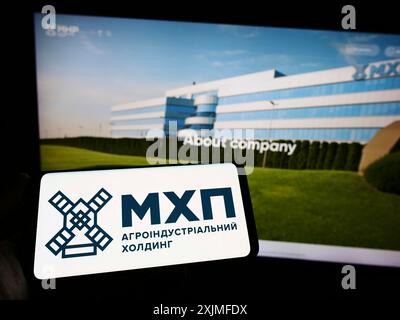 Stuttgart, Germany, 06-18-2022: Person holding smartphone with logo of Ukrainian company Myronivsky Hliboproduct (MHP) on screen in front of website. Stock Photo