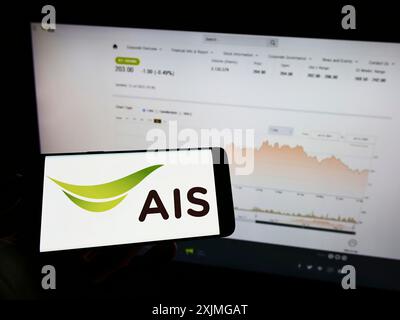 Stuttgart, Germany, 07-13-2022: Person holding cellphone with logo of Thai company Advanced Info Service (AIS) on screen in front of business Stock Photo