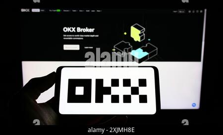Stuttgart, Germany, 07-17-2022: Person holding cellphone with logo of crypto company Aux Cayes FinTech Co. Ltd. (OKX) on screen in front of webpage. Stock Photo