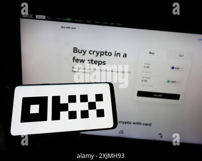 Stuttgart, Germany, 07-17-2022: Person holding smartphone with logo of crypto company Aux Cayes FinTech Co. Ltd. (OKX) on screen in front of website. Stock Photo